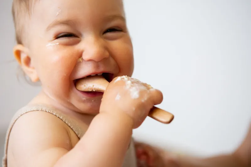 Bambina che ride con la crema in bocca