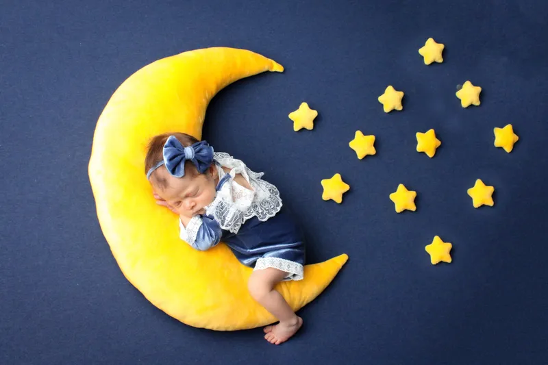 Neonata addormentata su una luna gialla fra le stelle
