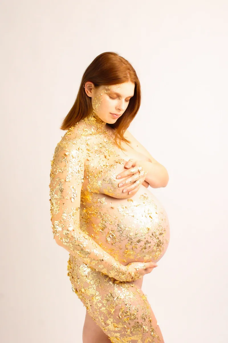Donna incinta con il corpo decorato in oro