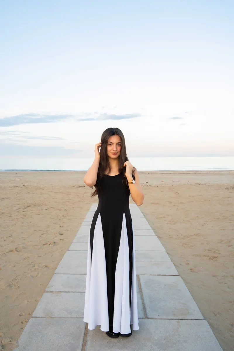 Ragazza in abito bianco e nero su una passerella in spiaggia