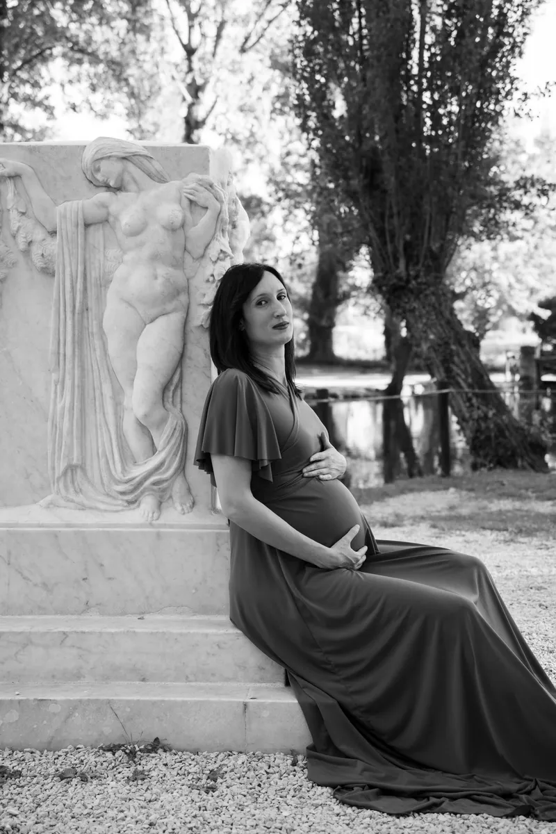 Donna incinta appoggiata a una statua in bianco e nero