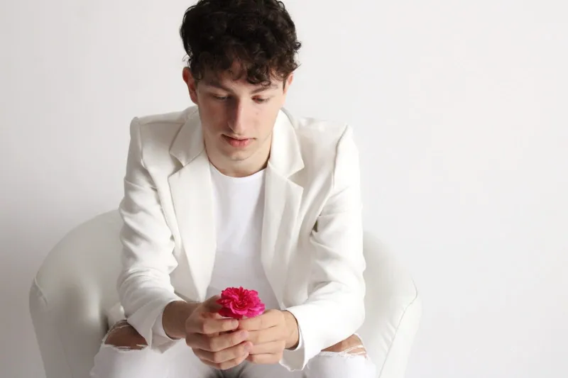 Ragazzo in giacca bianca con una rosa