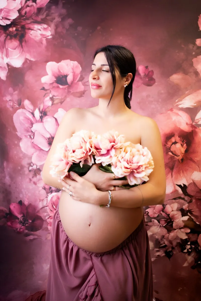 Donna incinta con un mazzo di peonie su fondo a fiori