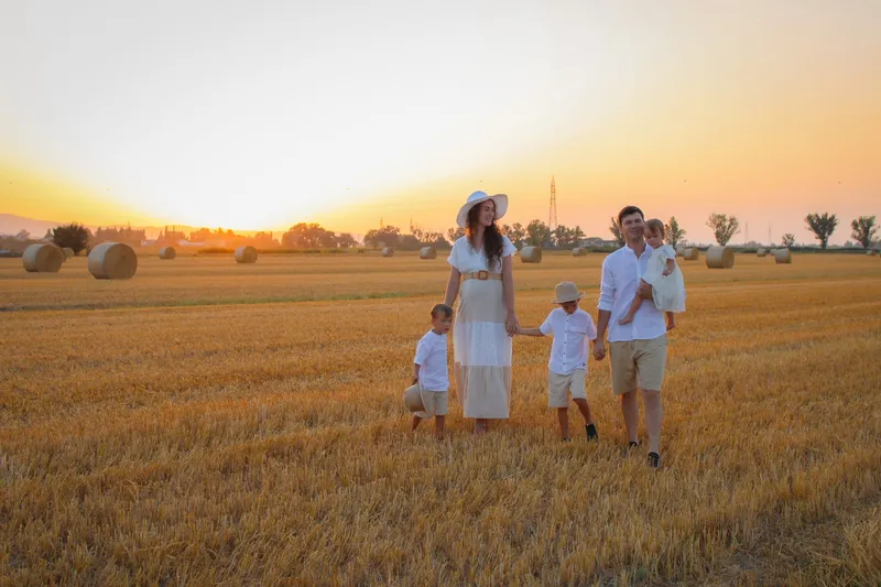 Famiglia con tre bambini in un campo di grano al tramonto