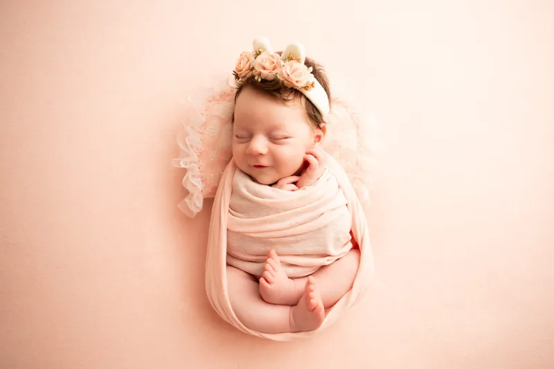 Neonata avvolta in rosa con una coroncina di fiori