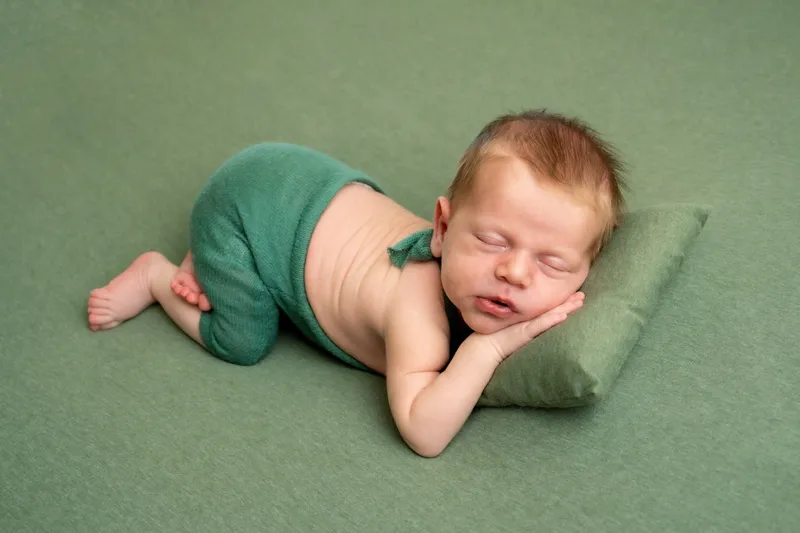 Neonato addormentato su un cuscino verde