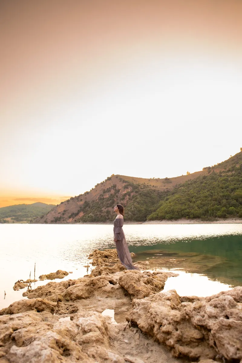 Ragazza sulle rocce di un lago al tramonto
