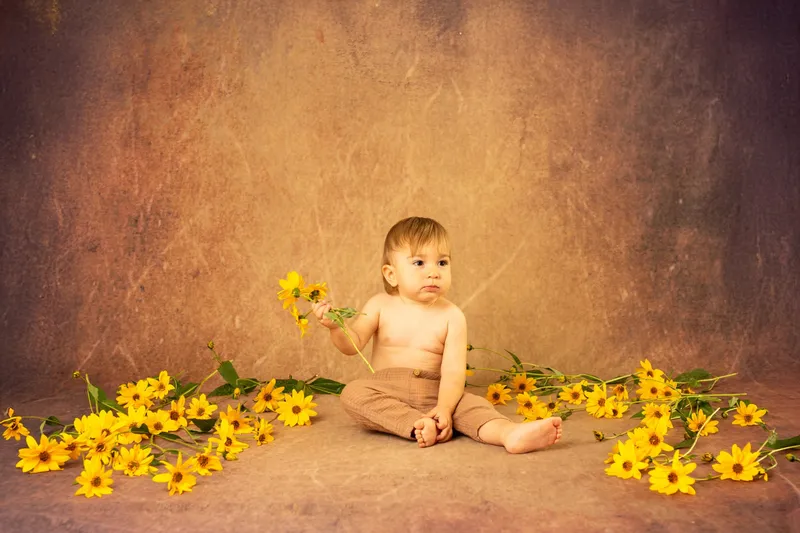 Bambino seduto fra fiori gialli