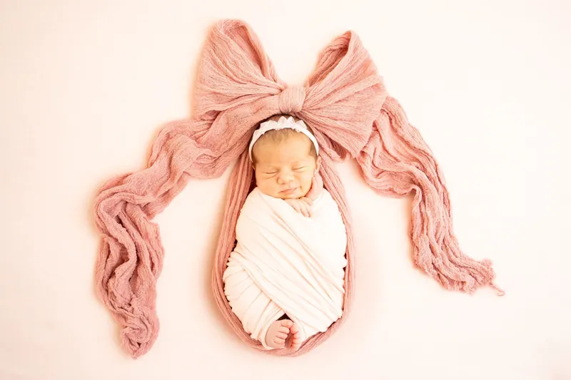 Neonata avvolta con un grande fiocco rosa