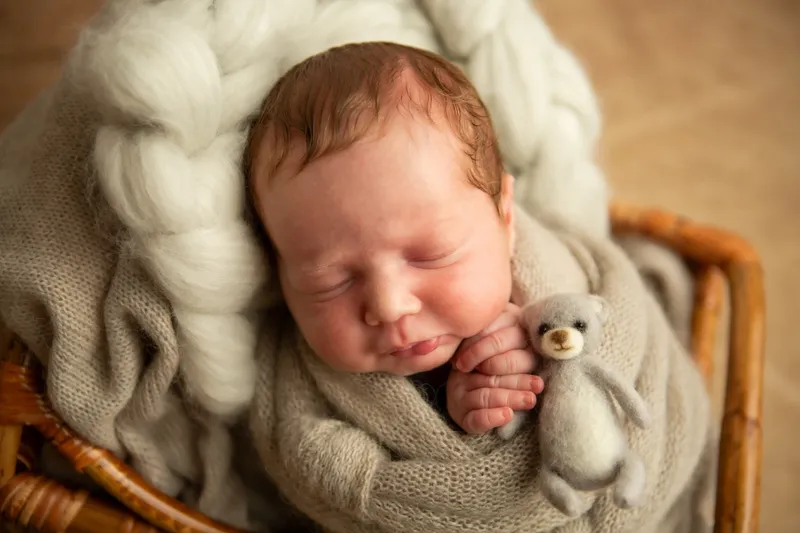 Primo piano di neonato con un orsetto di lana