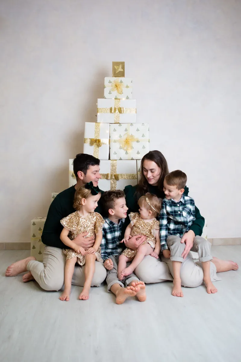Famiglia con quattro bambini davanti a un albero di pacchi