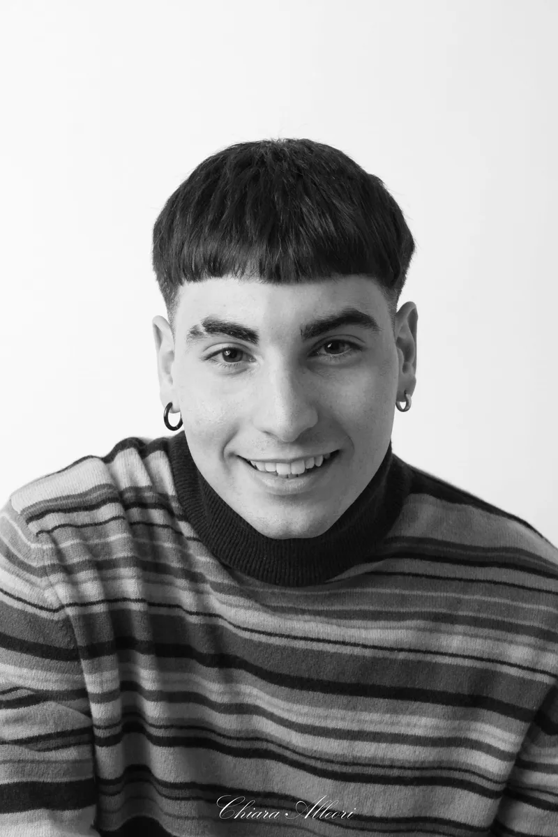 Ragazzo sorridente con maglione a righe in bianco e nero