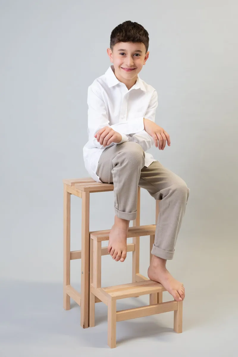 Bambino seduto su uno sgabello di legno