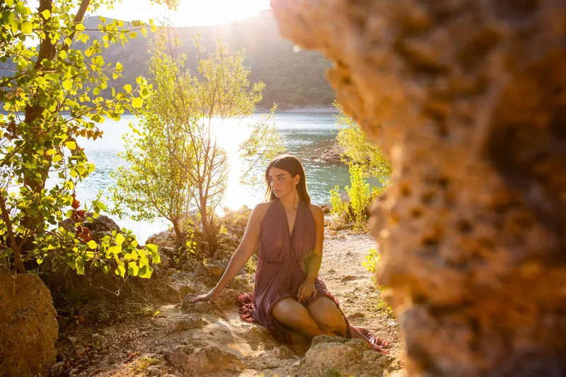Ragazza seduta sulle rocce in riva al lago