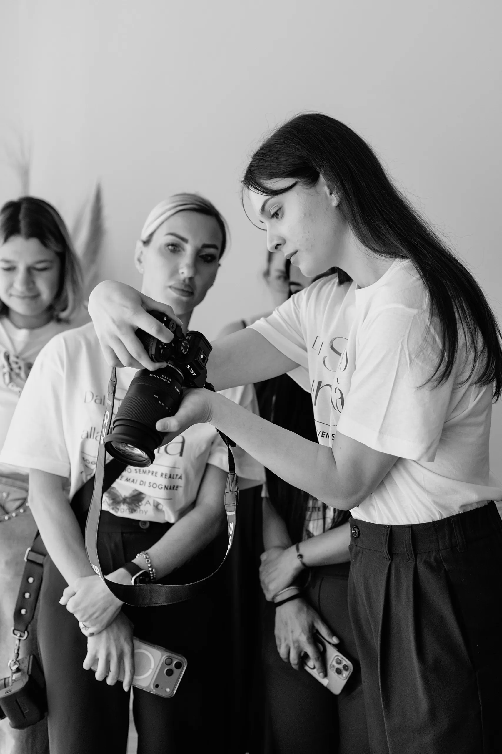 Chiara a un corso di fotografia, con la fotocamera in mano mentre osserva uno scatto insieme ad altre partecipanti